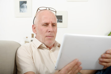 mature man having eyesight problems, he using  tablet