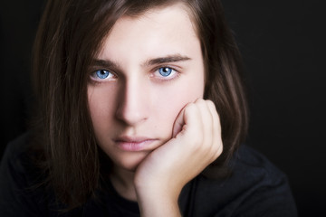 A portrait of a handsome blue eyes teenager on dark background