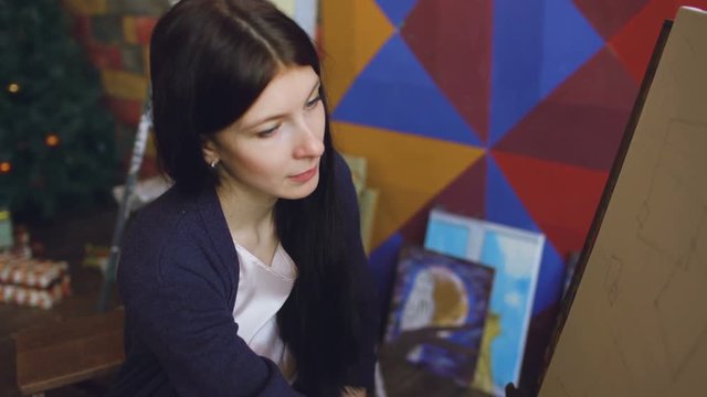 Young woman artist draw scetch wit pencil on easel canvas, preparing to paint picture