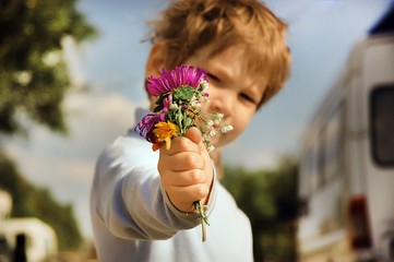 Boy with bouquet of wild flowers in a hand
