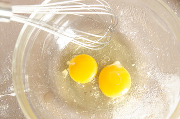 Beautiful picture of eggs in a white bowl with beaters near yolk
