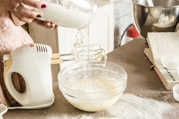 Kitchen table with flour and The bowl with flour and dough and with beaters.