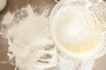 Kitchen table with flour and The bowl with flour and dough and with beaters.