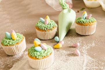 Beautiful cute Easter cupcakes with Easter decorations isolated on wood background while cooking by chef