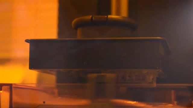Stereolithography DPL 3d printer create detail and liquid drips, platform slowly move with liquid close-up. Progressive modern additive technology 3D printing, create scaled model by UV polymerization