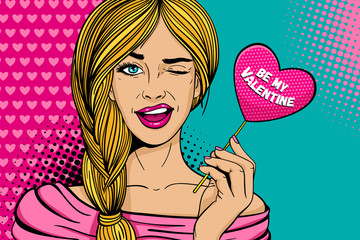 Pop art face. Young sexy blonde woman with pink paper with Be my Valentine lettering heart in her hand smiles and winks on dots background. Holiday party invitation vector poster in retro comic style.