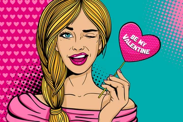 Pop-Art-Gesicht. Junge sexy blonde Frau mit rosa Papier mit Be my Valentine Schriftzug Herz in der Hand lächelt und zwinkert auf Punkthintergrund. Urlaubsparty-Einladungsvektorposter im Retro-Comic-Stil. © irina_levitskaya