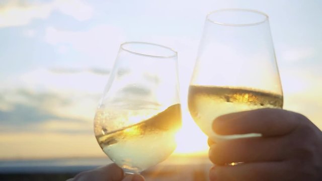 Businessmen toasting and drinking wine on the restaurant terrace over sunset in slowmotion with lense flare effects. Celebrating agreement. 1920x1080