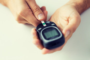 close up of man checking blood sugar by glucometer
