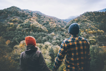 Couple Man and Woman in love together holding hands standing on bridge with mountains forest view...