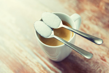 close up of white sugar on teaspoon and coffee cup