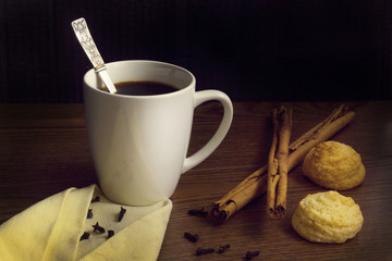 Cup coffee with cinnamon and cookies on wooden table