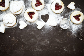 Homemade heart shaped linzer cookies with jam on wooden texture background, top view, copy space 
