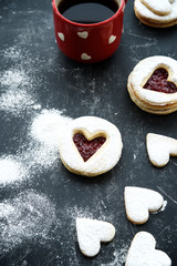 Homemade heart shaped linzer cookies with jam on wooden texture background 
