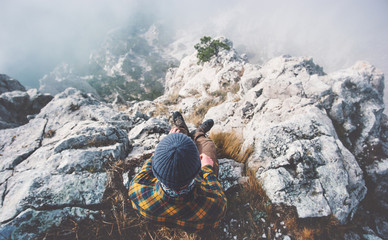 Traveler man relaxing alone on rocky mountain summit over clouds Travel Lifestyle success concept...