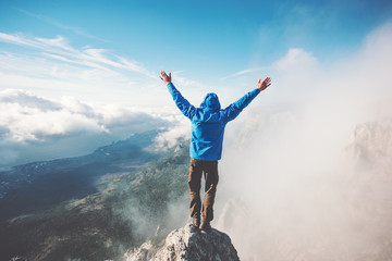Man Traveler on mountain summit enjoying aerial view hands raised over clouds Travel Lifestyle...