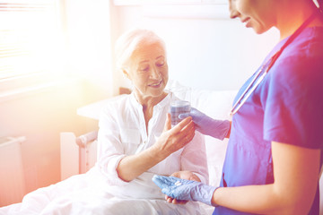 Obraz premium nurse giving medicine to senior woman at hospital