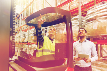 men with tablet pc and forklift at warehouse