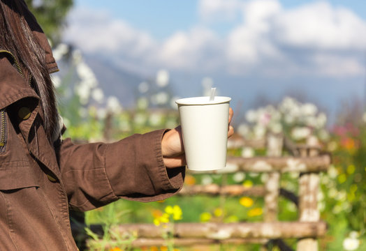 femals holding the hot of coffee in the garden with relaxed feel