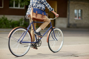 young hipster man with bag riding fixed gear bike