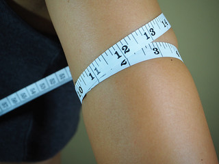 Woman measure her arm fat by measuring tape
