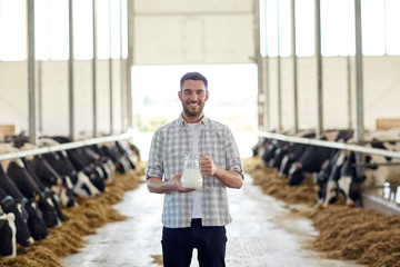 man or farmer with jug of cows milk on dairy farm