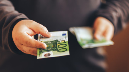 Man giving money cash. Male hands holding hundred euro banknote bill. Credit 