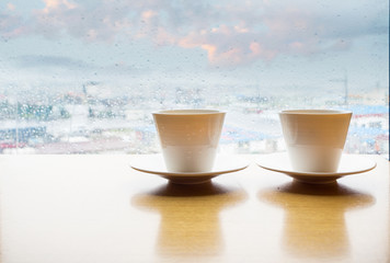 Two coffee cup on a blured rainy day window background