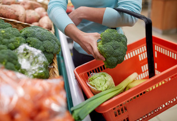 woman with basket buying broccoli at grocery store