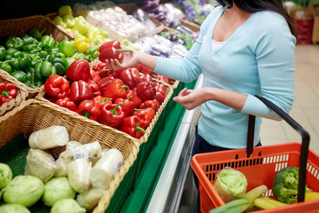 woman with basket buying peppers at grocery store