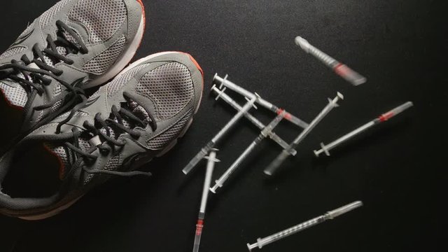 DOPING: Slow motion shot of Syringes fall near a sneakers - top view