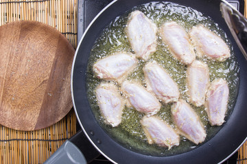 Chef frying chicken wings in pan
