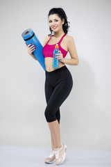 Naklejka premium Portrait of happy young woman holding rolled up exercise mat ove