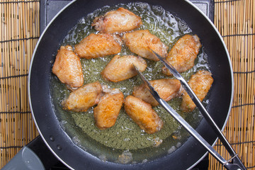 Chef frying chicken wings in pan