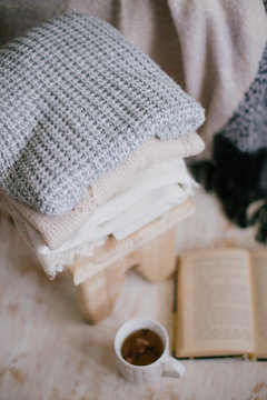 Still life details of interior: knitted clothes on a vintage wooden floor, cup of tea and book