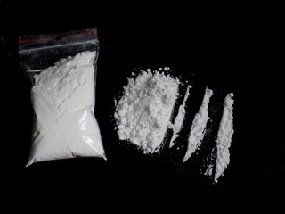 Cocaine drug powder bag, pile and lines on black background