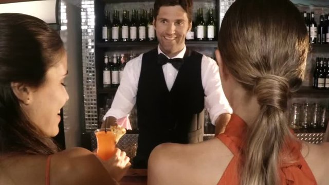 Waiter serving cocktail to customers