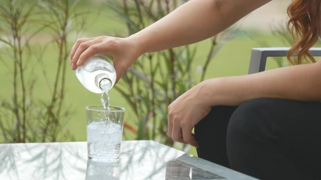 4k of woman hand serving water in crystal glass on table
