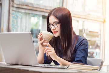 young asian woman using technology on her laptop computer and ho