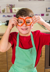 Funny adorable boy with sliced paprika on eyes