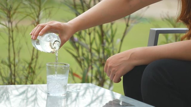 4k of woman hand serving water in crystal glass on table