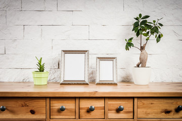 wooden shelf with frames and flowers against a brick wall