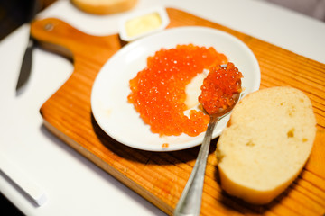Red caviar with lemon, bread and butter on wooden board white table background. Close up image of delicacy food luxury lifestyle