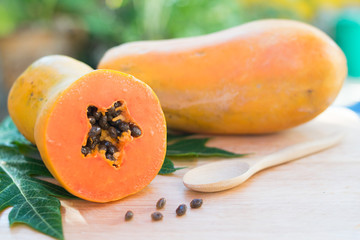 Ripe papaya with green leaf on wooden background