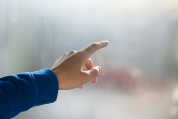 Hand draws on cold fogged window background, closeup image