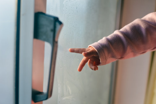 Hand draws on cold fogged window background, closeup image