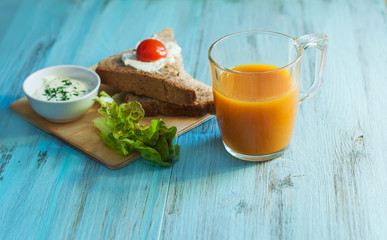 Завтрак, бутерброд с сыром и овощами и сок на деревянном фоне. Крупным планом  
