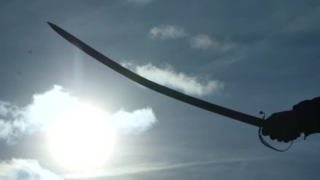 hands with sabers on battle field against sun slow motion