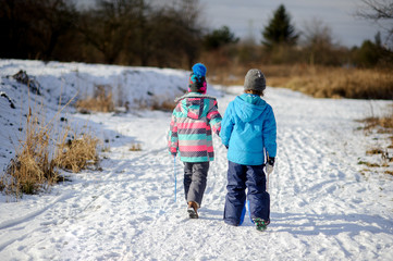 Fototapeta na wymiar Two children of younger school age, boy and girl, walk on first snow.