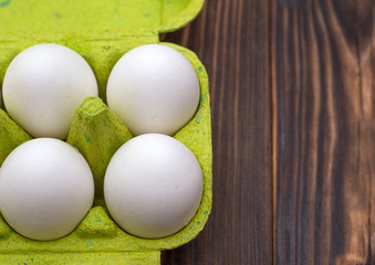 White eggs in a green tray on a wooden background. View from above
